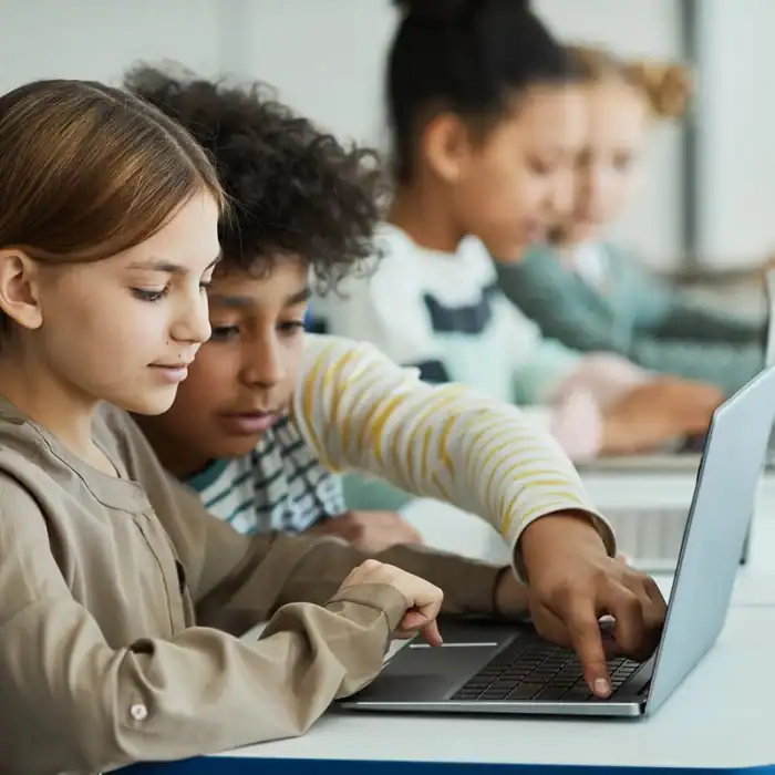 Two elementary students working together on a laptop in school