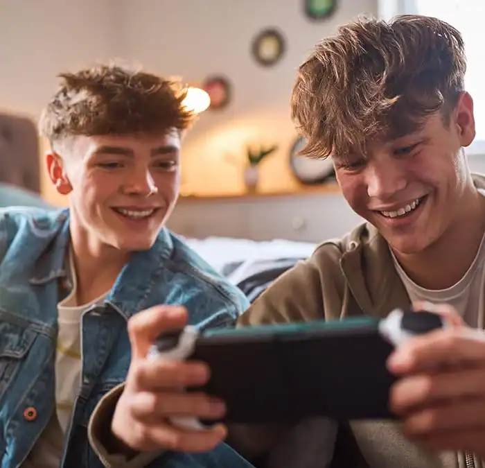 Two teens laughing while looking at a smartphone screen