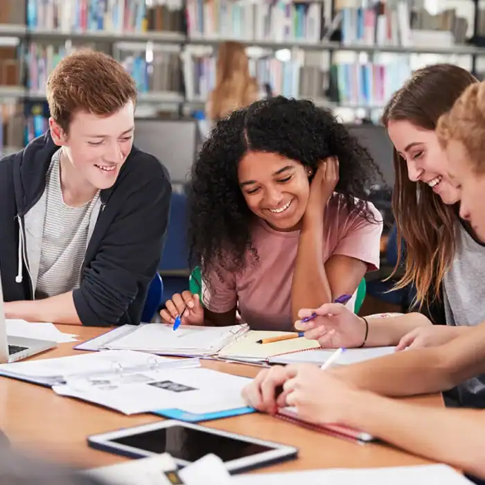 Four high school students collaborate on schoolwork in a library