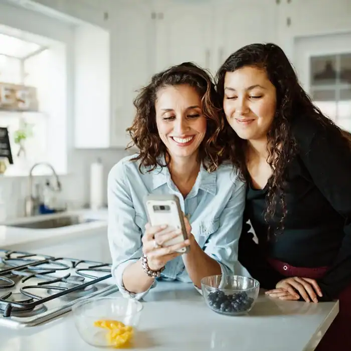 Mother and daughter in a kitchen looking at a smartphone together