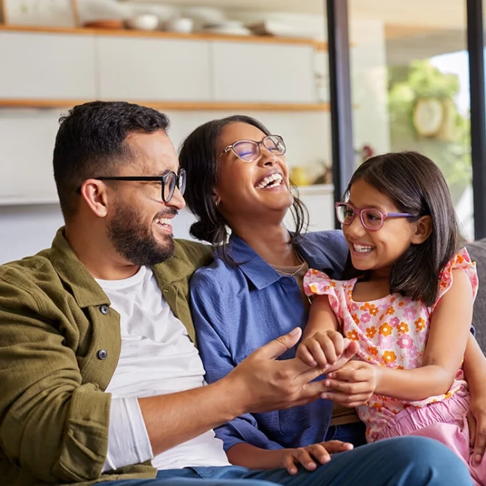 Mother, father and daughter laughing together at home on a couch