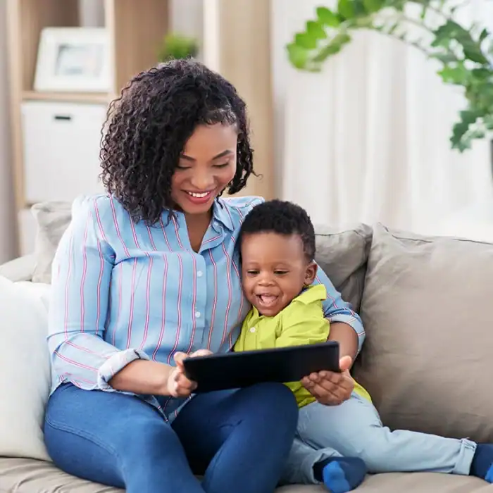 Mother and young son smiling while looking at a tablet