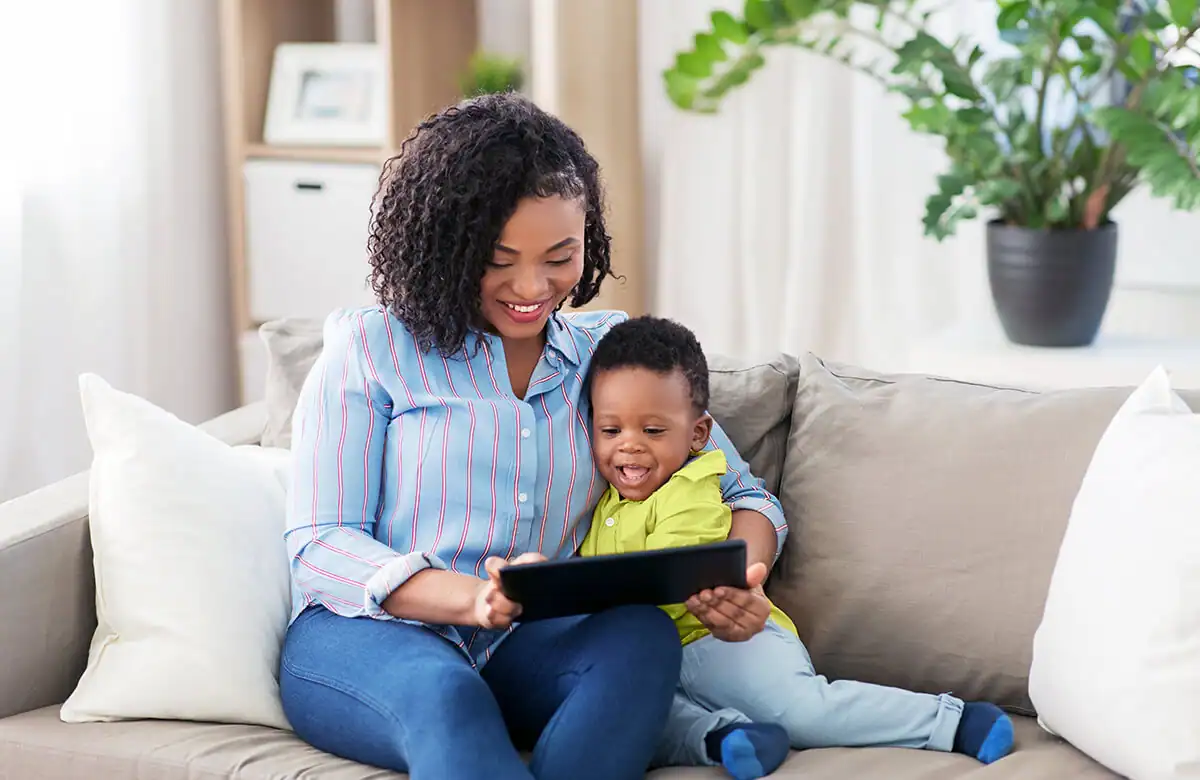 Mother and young son smiling while looking at a tablet