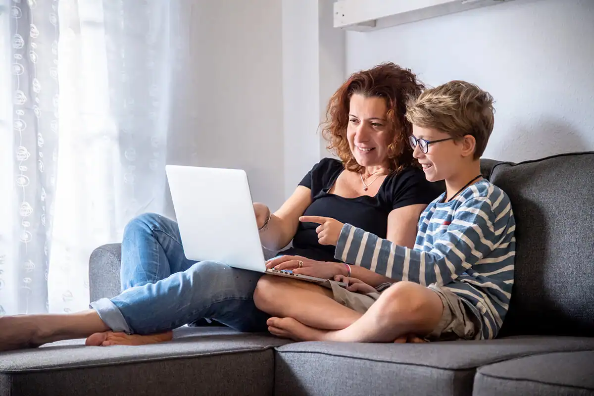 Mother and son looking at a laptop together and smiling at what they see on the monitor