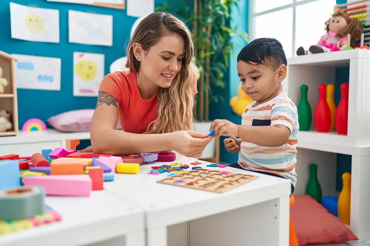 Preschool teacher handing toy letters to a young child