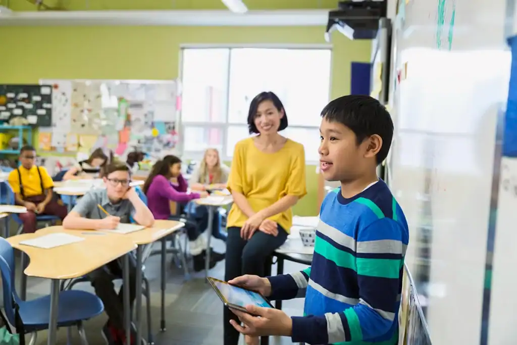 Student holding a tablet while presenting to classroom