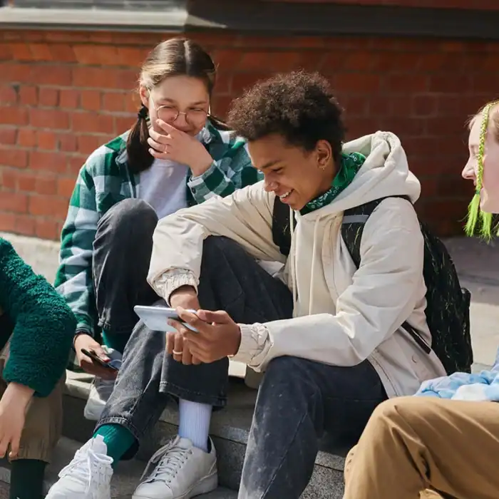 Four students laughing while looking at a smartphone