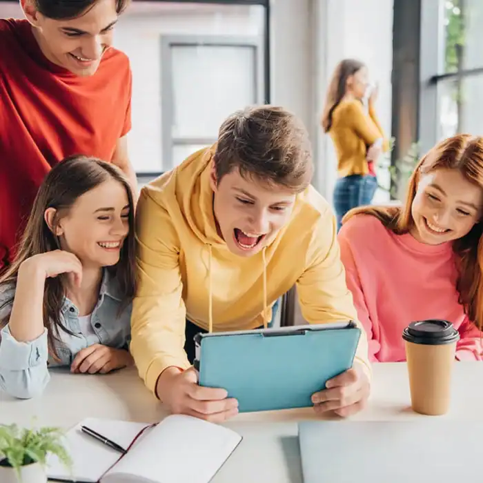Group of students looking at a tablet device and laughing