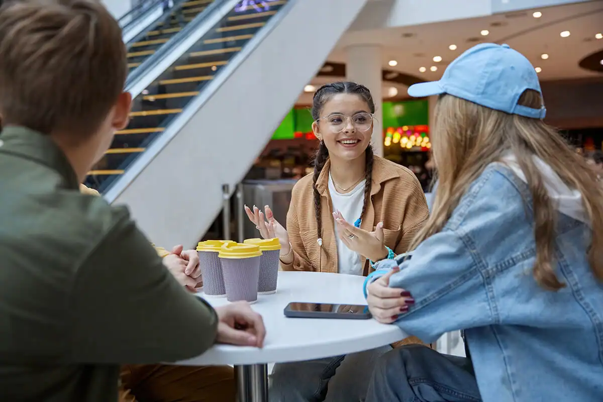 Teens socializing at a table in a mall food court