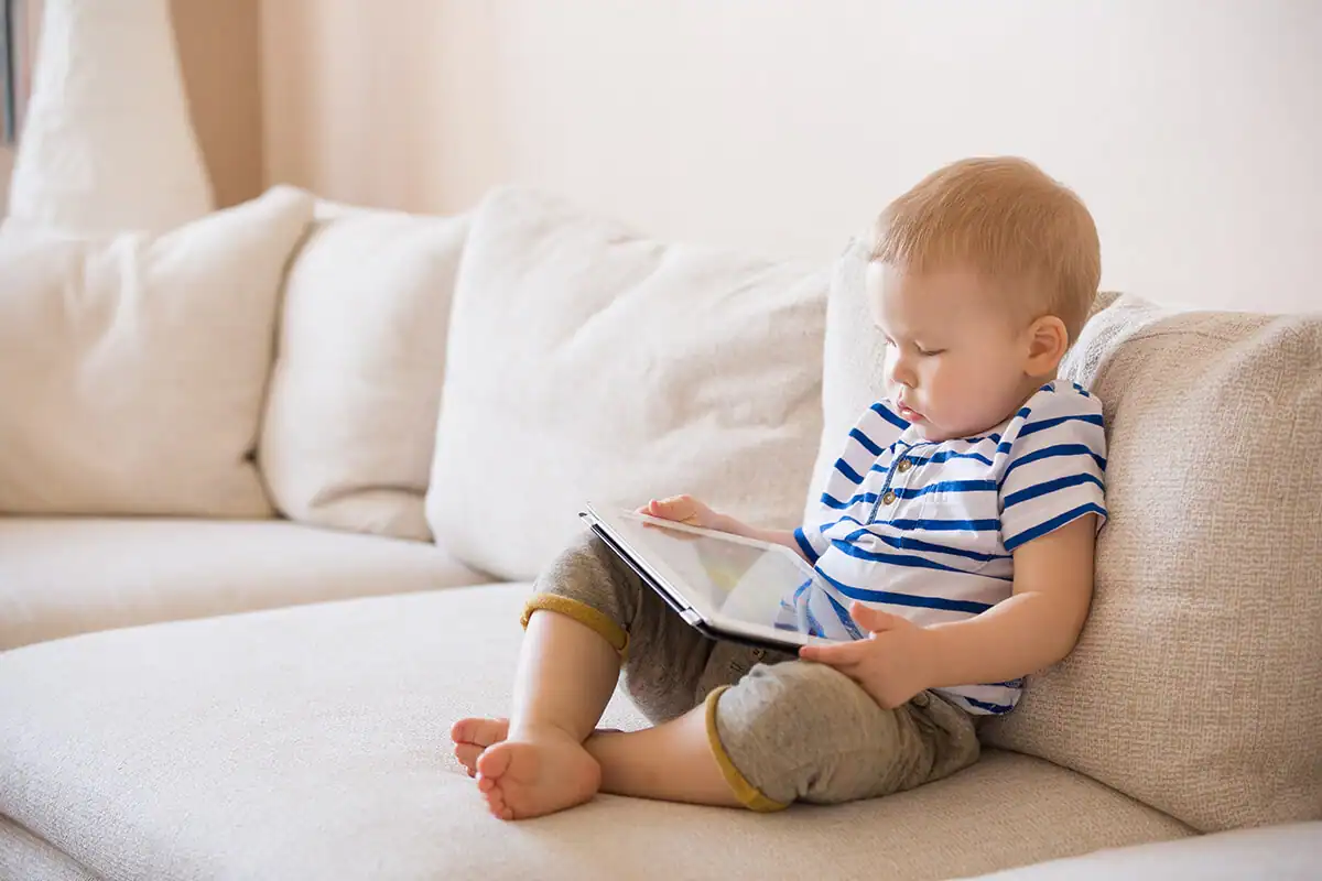 Young child using a tablet device on a couch