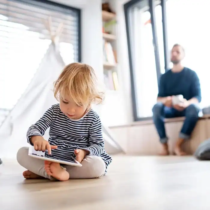Young child using a tablet device while his father observes